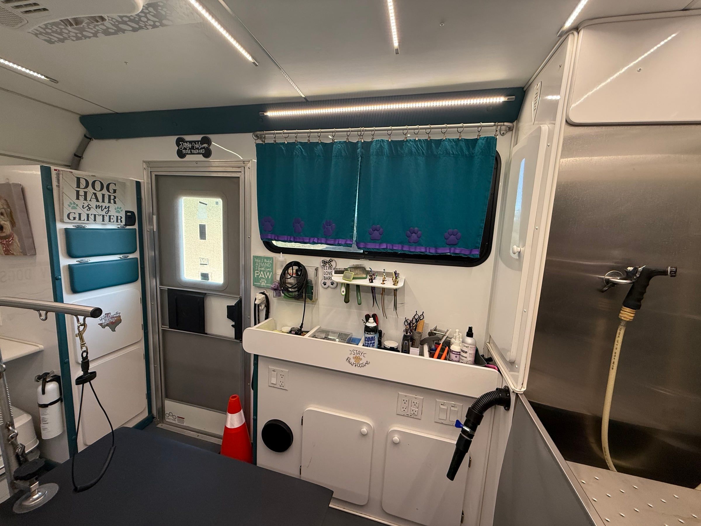 Tool station inside the trailer with shears, clippers, and brushes on the rail beneath a teal curtain