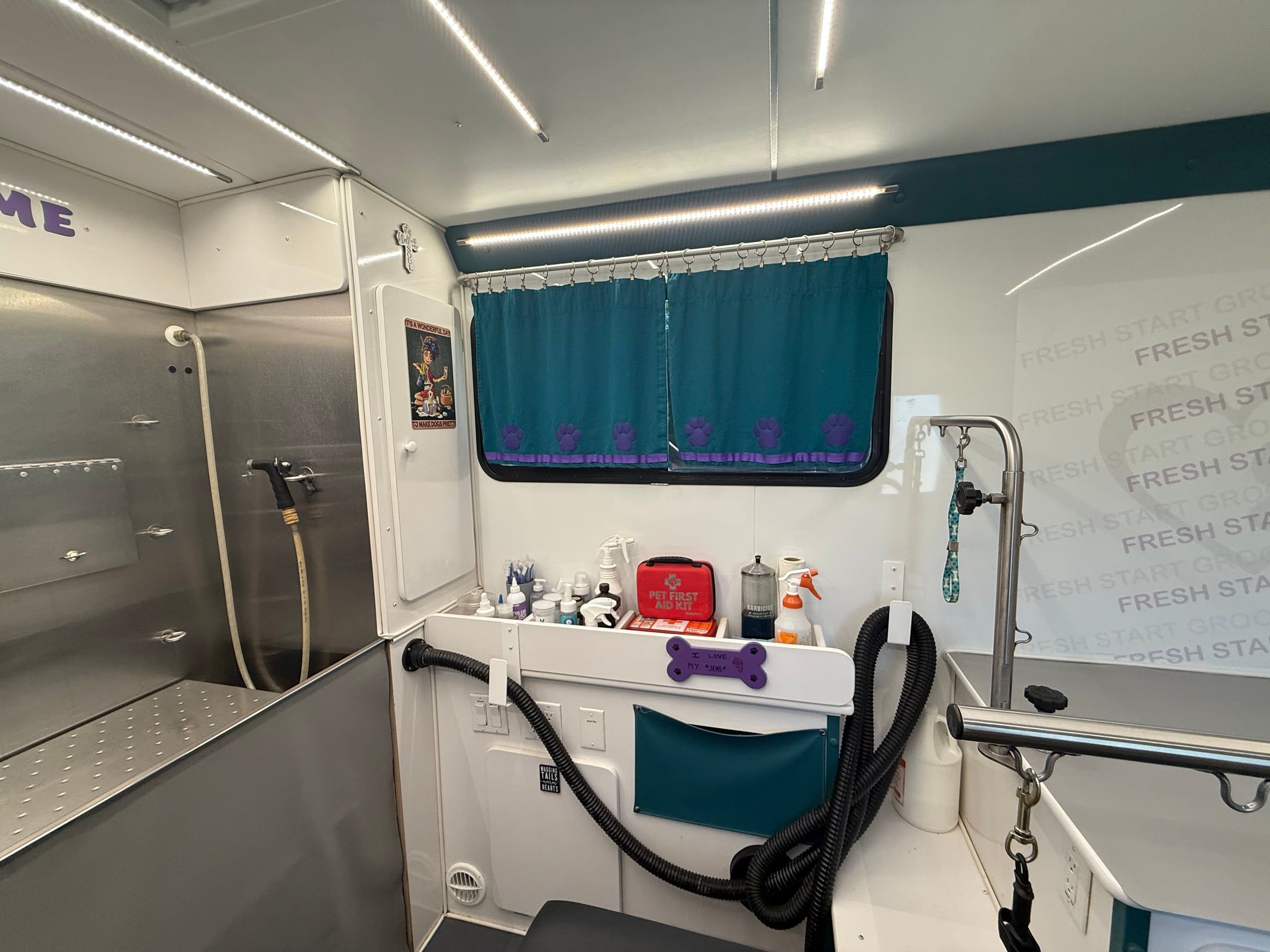 Stainless steel bath stall beside the pet first-aid kit inside the trailer